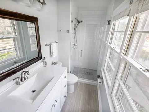 A clean, bright bathroom with a white vanity, a large mirror and a tiled glass shower