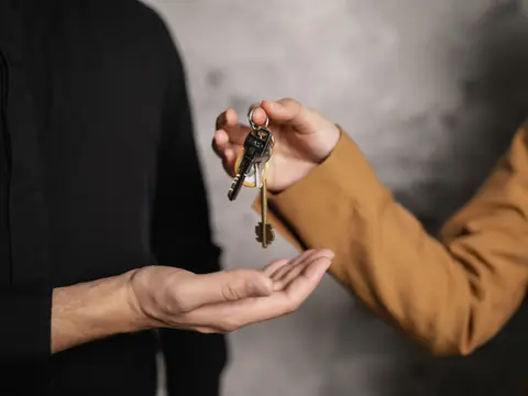 One person handing a set of keys to another person's open hand