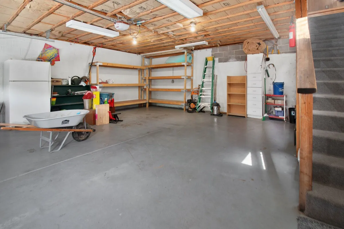 A spacious garage with organized storage shelves, tools, and a wheelbarrow, highlighting the importance of move out cleaning.